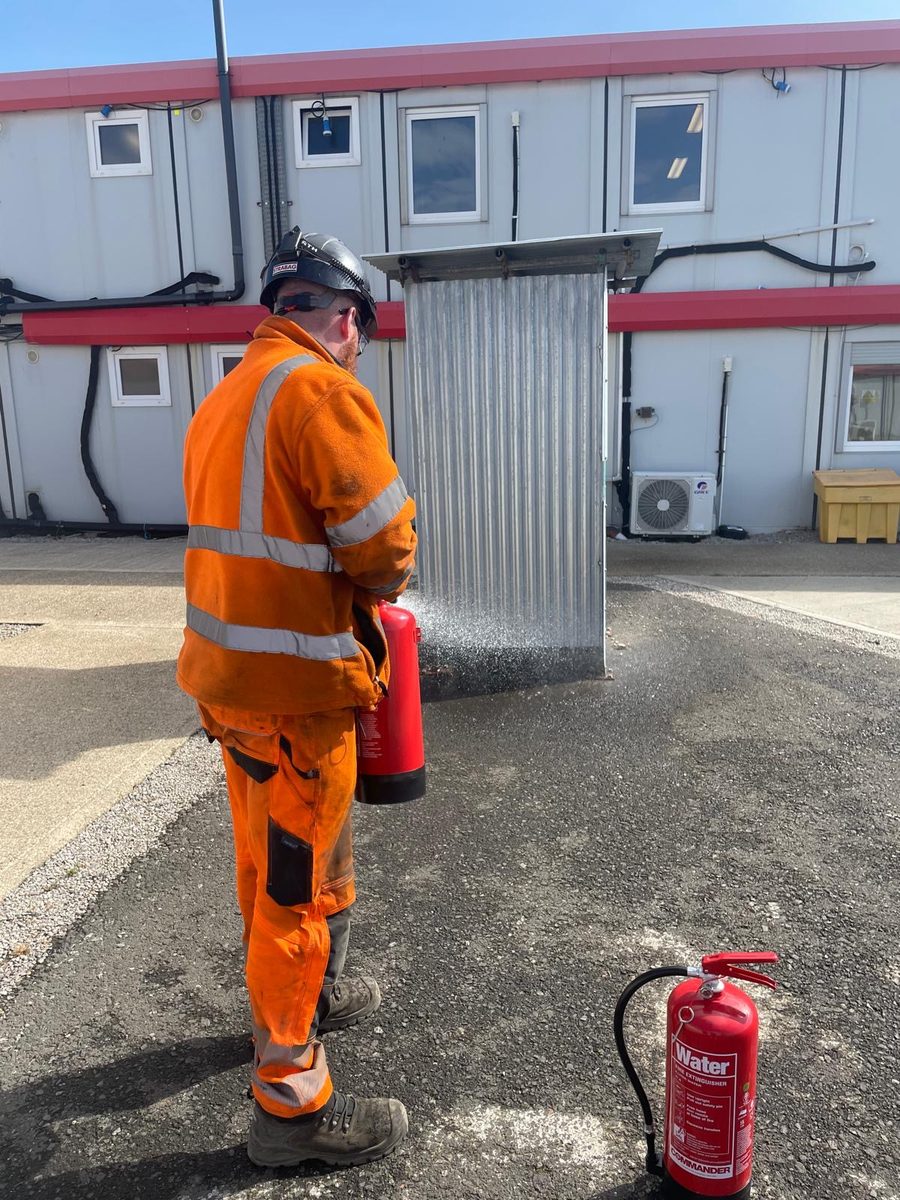 An instructor testing a fire extinguisher outdoors during Fire Warden training